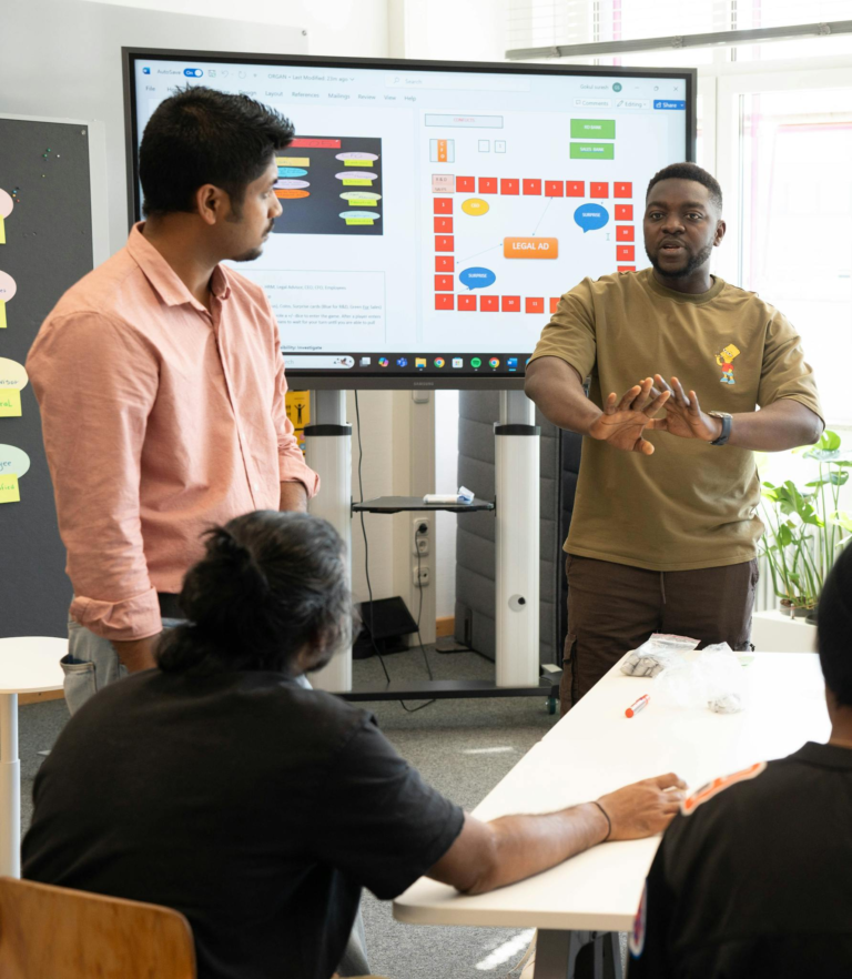 A diverse group of adults engaging in a teamwork session with a digital presentation in an office.